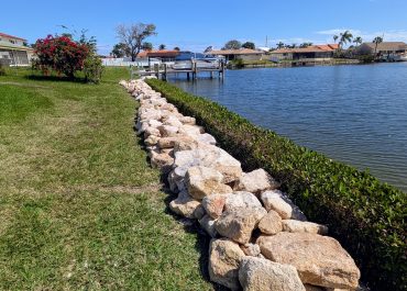 A picture after Coquina Seawall Installation on a canal with green grass next to the edge of a dock